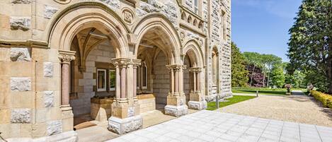 A historic stone building with arched entrances and a paved courtyard.
