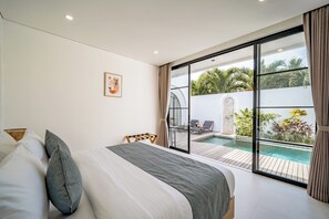 A bedroom with a bed, a view of a swimming pool, and a balcony with a view of the pool. - Maui Bingin Villas (Pecatu)
