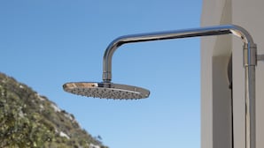 A modern showerhead with a curved design, mounted on a wall. - Aires Villa (Agios Nikolaos)