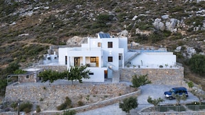 A modern white building with a stone base, a rooftop pool, and a staircase leading to the upper levels. - Aires Villa (Agios Nikolaos)