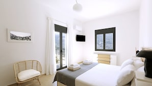 A bedroom with a bed, a chair, a window, and a picture on the wall. - Aires Villa (Agios Nikolaos)