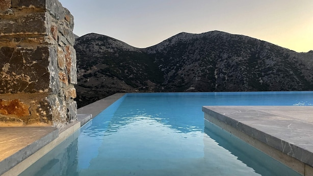 A swimming pool with stone walls and a view of mountains. - Aires Villa (Agios Nikolaos)