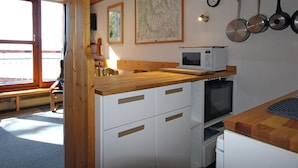 Une cuisine avec des meubles en bois, un four à micro-ondes et une cuisinière. Il y a une fenêtre donnant sur l'extérieur.