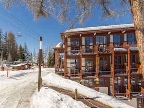 A multi-story wooden building with balconies, surrounded by snow and trees. - Comfortable duplex, ski-in/ski-out, 6 ppl, southwest balcony (Les Arcs 1800)