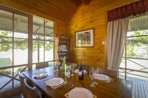 Une table de salle à manger en bois, dressée pour quatre personnes, avec des verres à vin, des assiettes et des couverts.
