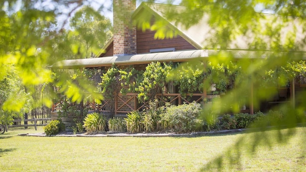 A rustic building with a chimney, surrounded by lush greenery and a well-maintained lawn. - Silky Oak Cottage & Studio - Delightful country cottage along popular Hermitage Rd (Pokolbin)