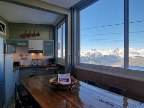 A kitchen with a view of snow-capped mountains through large windows.