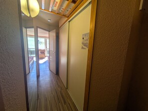 A hallway with a wooden floor, a sliding door, and a ceiling with exposed beams and insulation.