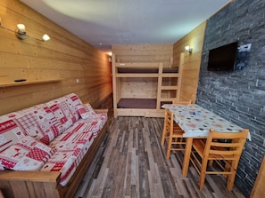 Um quarto aconchegante com sofá de madeira, uma mesa pequena e uma cama beliche.