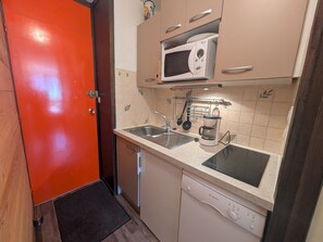 A compact kitchen with a microwave, coffee maker, and dishwasher.
