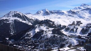 A mountainous landscape with snow-covered peaks and a small town nestled at the base. - Charming Ski-In Studio · Pets Welcome (Plagne Aime 2000)