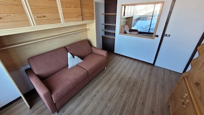 A compact room with a wooden bunk bed, a sofa, and a small window. - Charming Ski-In Studio · Pets Welcome (Plagne Aime 2000)