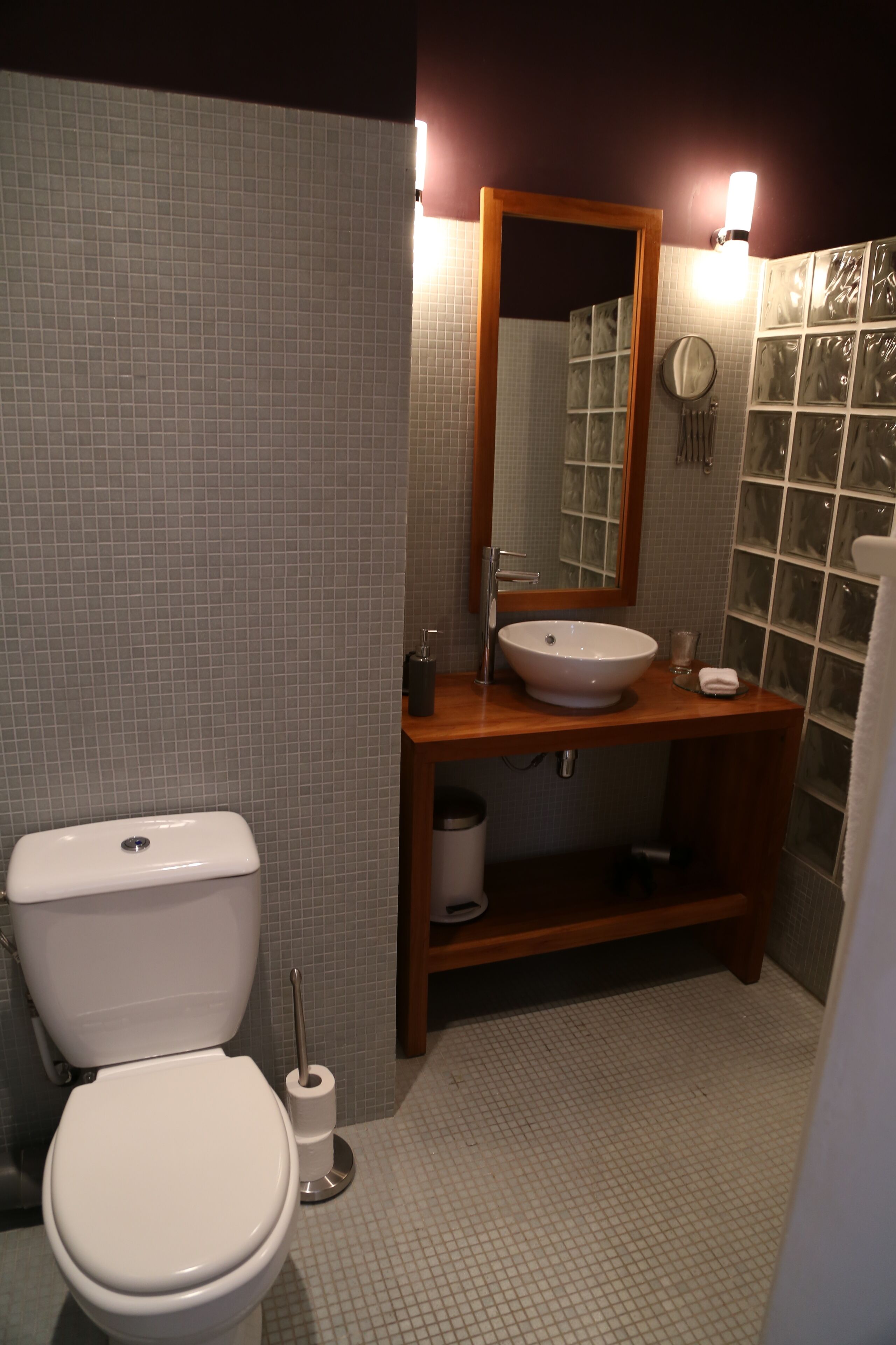 A bathroom with a toilet, sink, mirror, and tiled walls.