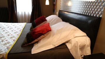 A neatly made bed with a floral bedspread, a headboard with a textured pattern, and a bedside table with a lamp.