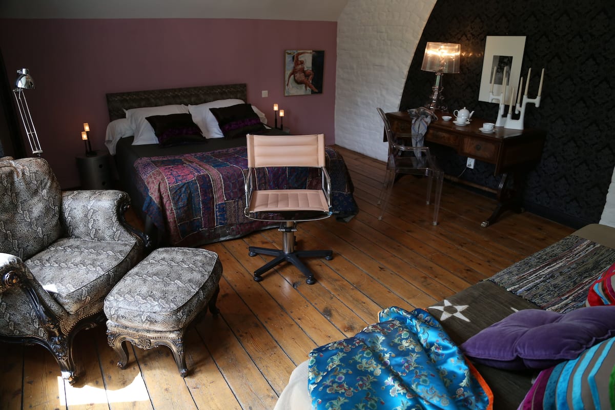 A bedroom with a bed, a chair, a desk, and a dresser.