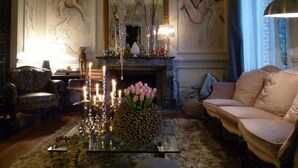 A cozy living room with a fireplace, a sofa, and a coffee table with candles and flowers.
