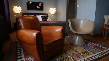 A room with a brown leather chair, a modern armchair, a patterned rug, and two hanging lamps.