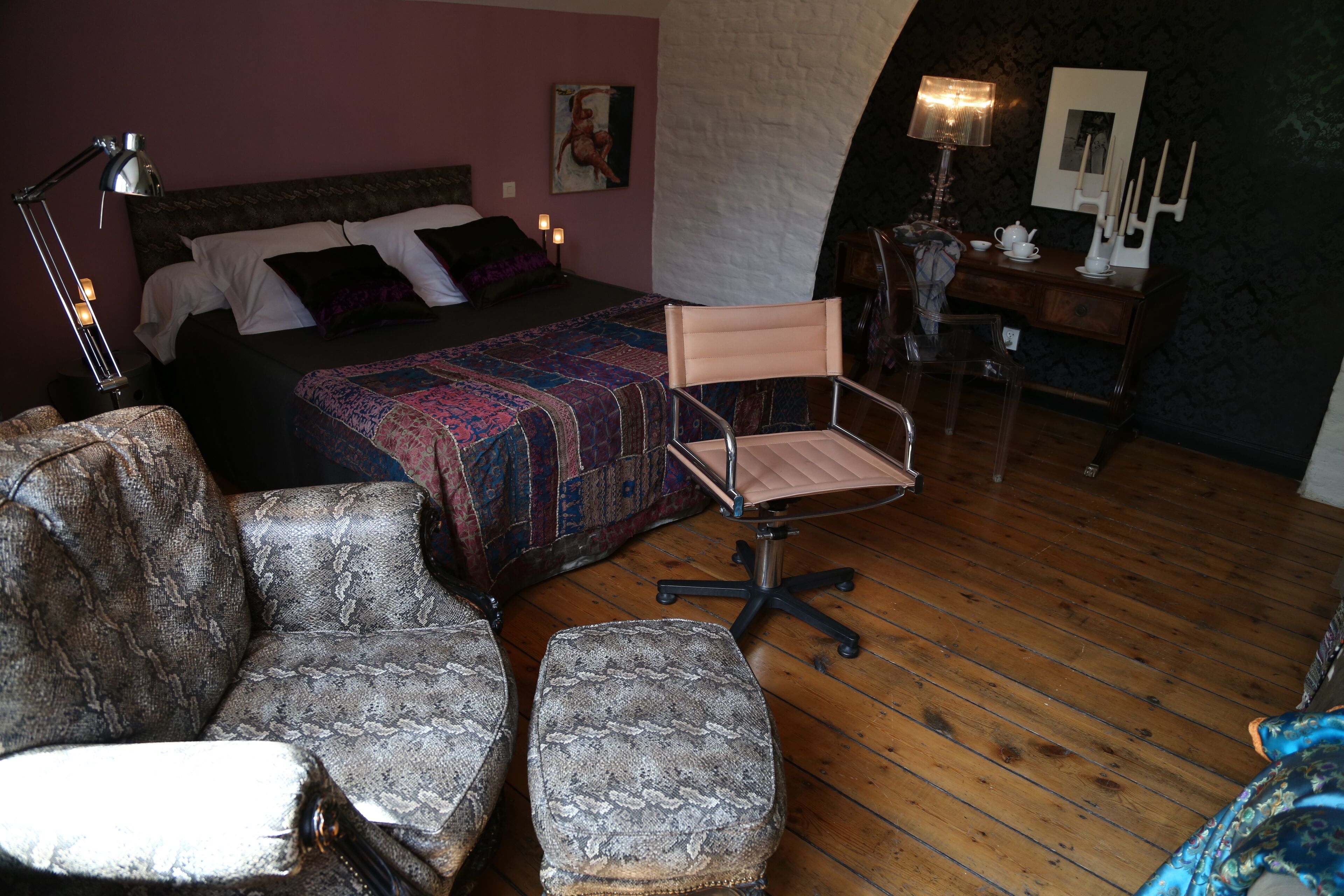 Une chambre à coucher avec un lit, deux chaises, un bureau et une lampe.