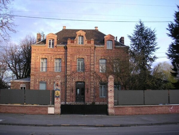 A brick building with a central entrance, multiple windows, and a gated driveway. - LE GRAND DUC (Valenciennes)