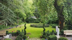 A garden with a lawn, potted plants, a stone pathway, and a wooden bench.
