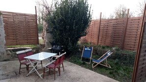 A patio with a table and chairs, a blue folding chair, and a small table with a beer mat. - Maison DE Campagne AU Calme à 25 min de Provins (Soligny-les-Étangs)