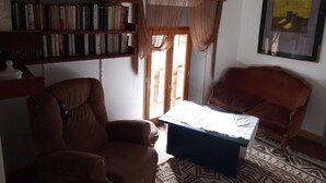 A living room with a brown armchair, a wooden coffee table, a bookshelf, and a framed picture on the wall. - Maison DE Campagne AU Calme à 25 min de Provins (Soligny-les-Étangs)