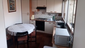 A compact kitchen with a dining table, a stove, a microwave, and a window. - Maison DE Campagne AU Calme à 25 min de Provins (Soligny-les-Étangs)