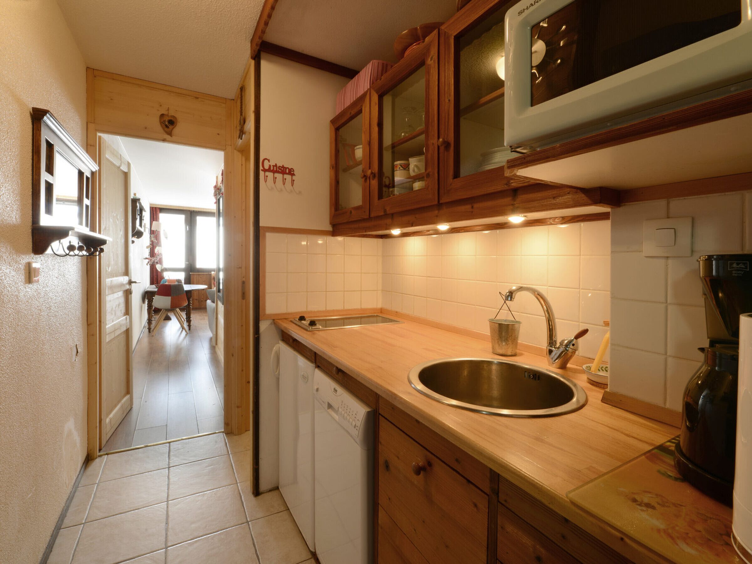 A kitchen with wooden cabinets, a stainless steel sink, and a tiled backsplash.