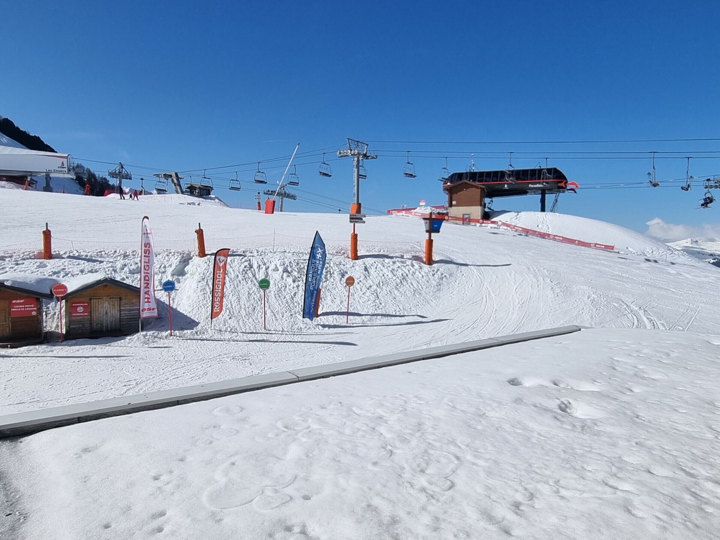 Une station de ski dotée d’un télésiège, de pistes de ski et d’un petit bâtiment.