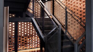 A staircase with metal railings and a brick wall with a geometric pattern. - Monocolo Boutique Hotel (Kota Kinabalu)