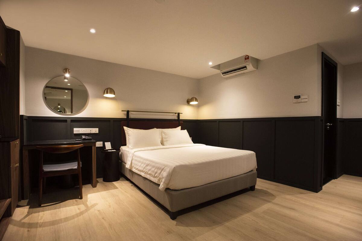 A modern bedroom with a large bed, a desk, a chair, and a mirror.