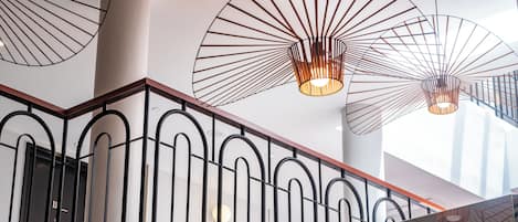 A modern interior with a staircase, metal railings, and pendant lighting fixtures.