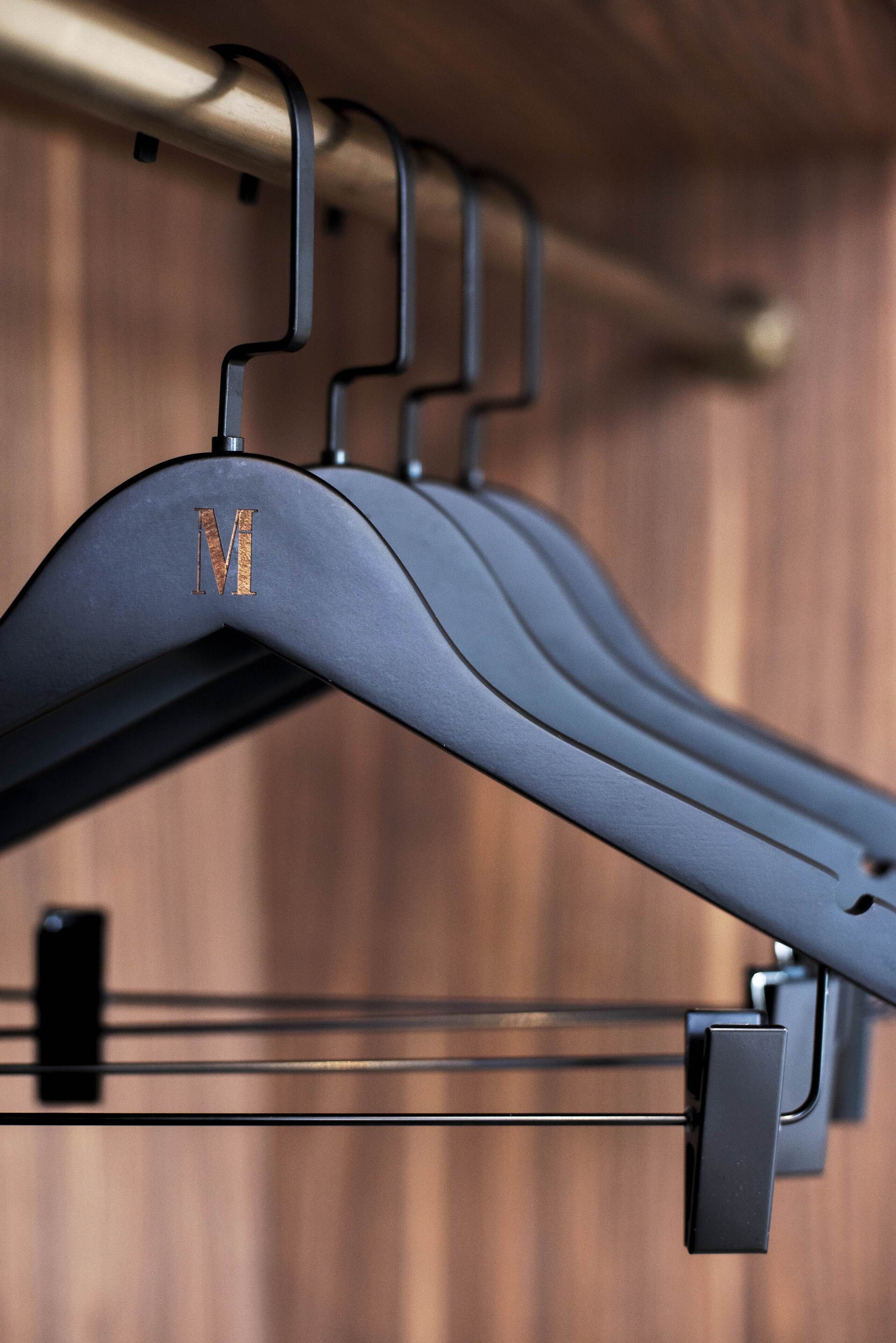 A metal coat rack with a single hanging garment marked with the letter "M".