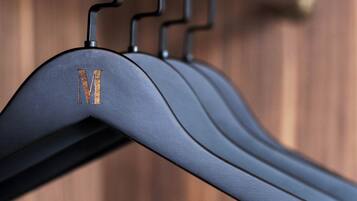 A metal coat rack with a single hanging garment marked with the letter "M".
