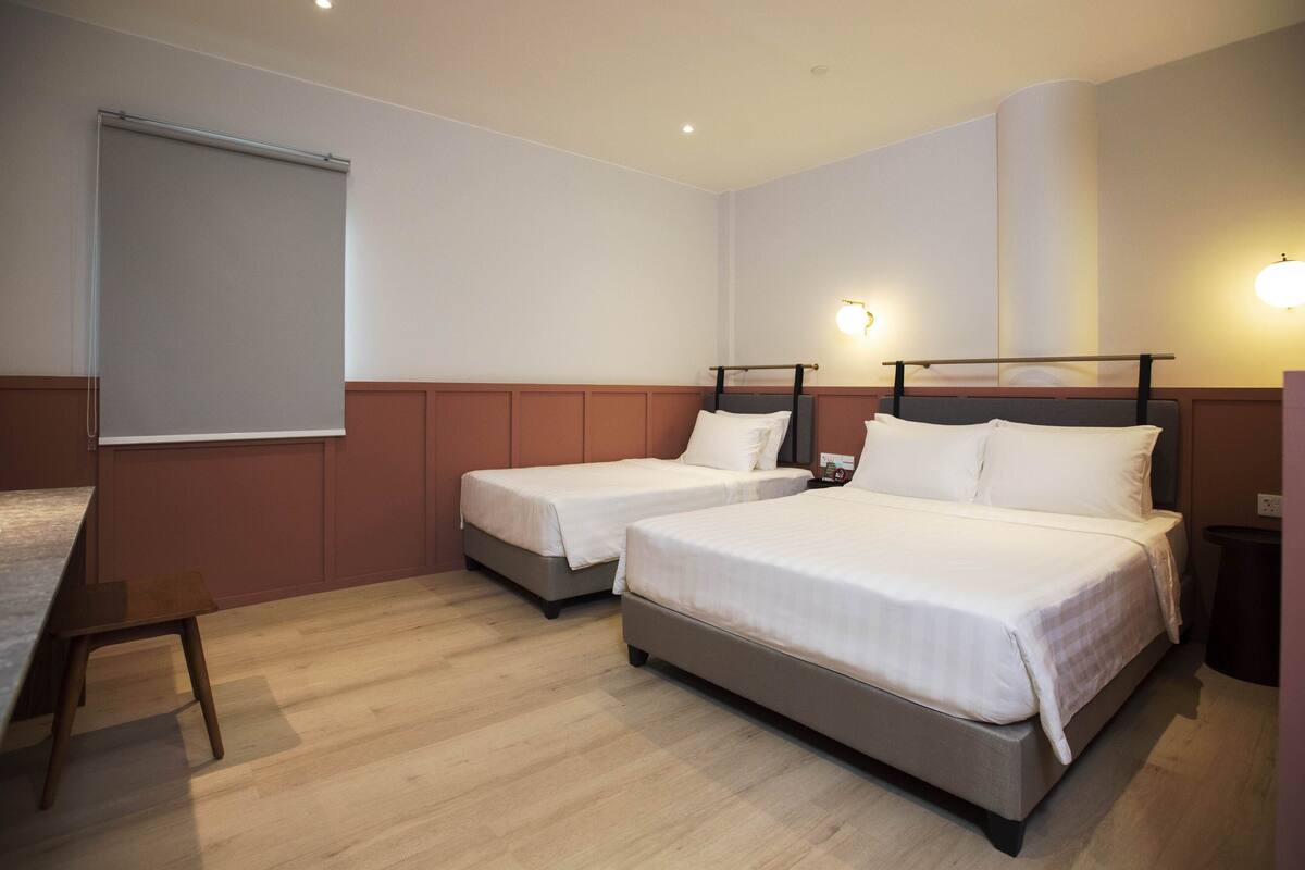 A hotel room with two single beds, a desk, and a large window.