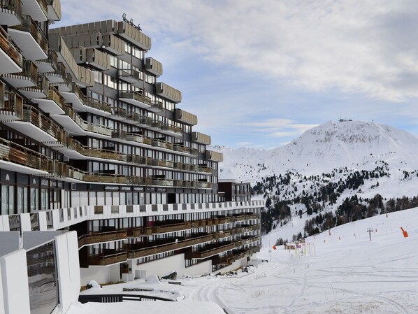 A multi-story hotel with balconies and a ski slope in the background.
