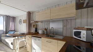 A modern kitchen with wooden cabinets, a dishwasher, a sink, and a microwave. - Comfortable renovated studio, south balcony, ski-in/ski-out (Plagne Aime 2000)