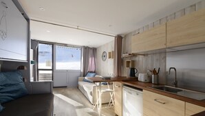 A compact, modern kitchen with a wooden countertop, a sink, and a dining area with a table and chairs. - Comfortable renovated studio, south balcony, ski-in/ski-out (Plagne Aime 2000)