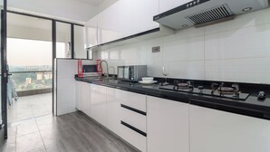 Una cocina moderna con armarios blancos, una encimera negra y vistas de la ciudad a través de un ventanal.
