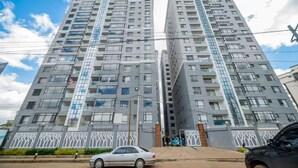 Un edificio residencial de gran altura con varios pisos, ventanas amplias y una entrada con portón.