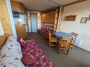 A compact room with a sofa, a small table, and a bed.