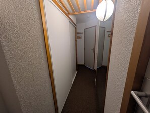 A narrow hallway with carpeted flooring, wooden trim, and a ceiling fan.