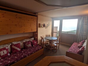 A cozy room with a wooden bunk bed, a round table with chairs, and a view through a large window. - Functional divisible studio ski-in/ski-out with Mont Blanc view (Plagne Aime 2000)