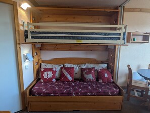 A bunk bed with a lower bed and a higher bunk, both with wooden frames.