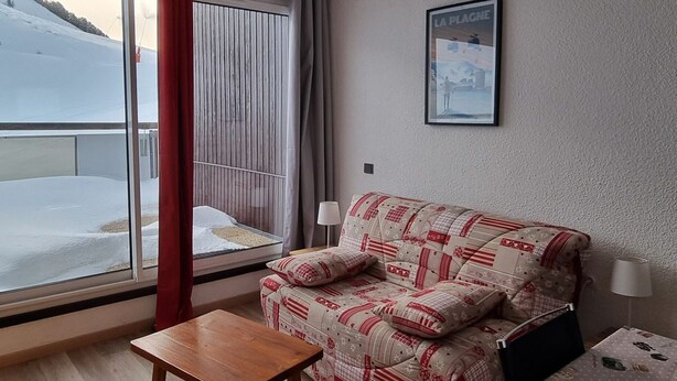 Ein gemütliches Zimmer mit einer Couch, einem kleinen Tisch und einem Fenster mit Blick auf eine verschneite Landschaft.