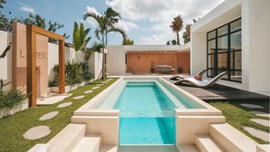 A modern outdoor pool area with a clear blue pool, steps leading down to the water, and lounge chairs on the right. - Villa Lamer (Canggu)