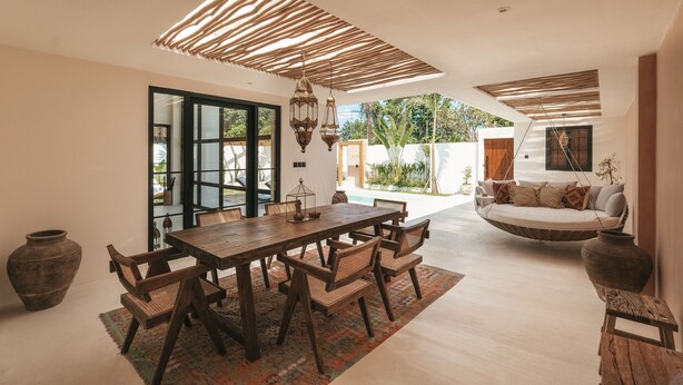 A spacious living area with a wooden dining table, wicker chairs, and a hanging swing sofa. - Villa Lamer (Canggu)
