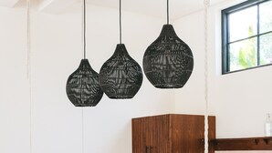 A modern kitchen with a white island, wooden bar stools, black woven pendant lights, and wooden cabinets. - Villa Lamer (Canggu)