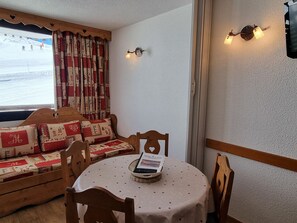A cozy room with a wooden bench, a round table with a polka dot tablecloth, and two wall-mounted light fixtures.