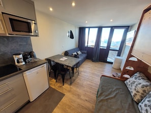 Un espacio habitable compacto con kitchenette, comedor, sofá y balcón con vistas.